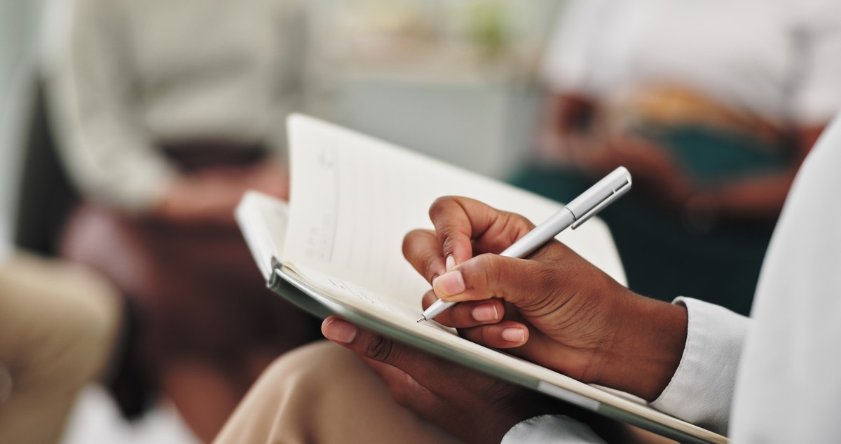 Person holding a clipboard and writing in a notebook.
