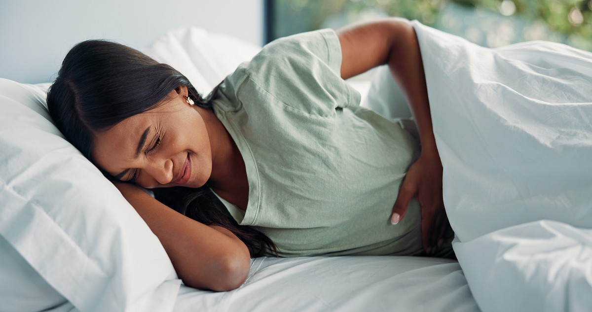 Pregnant woman resting in bed with a peaceful expression.